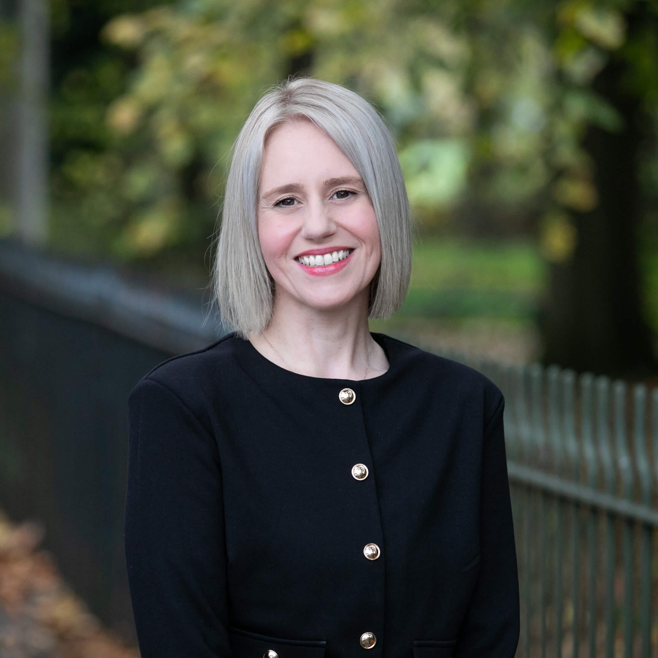 Mary Tmaira, a smartly-dressed solicitor, standing in a vibrant park.